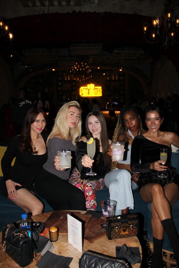 a group of women sitting on a couch holding drinks