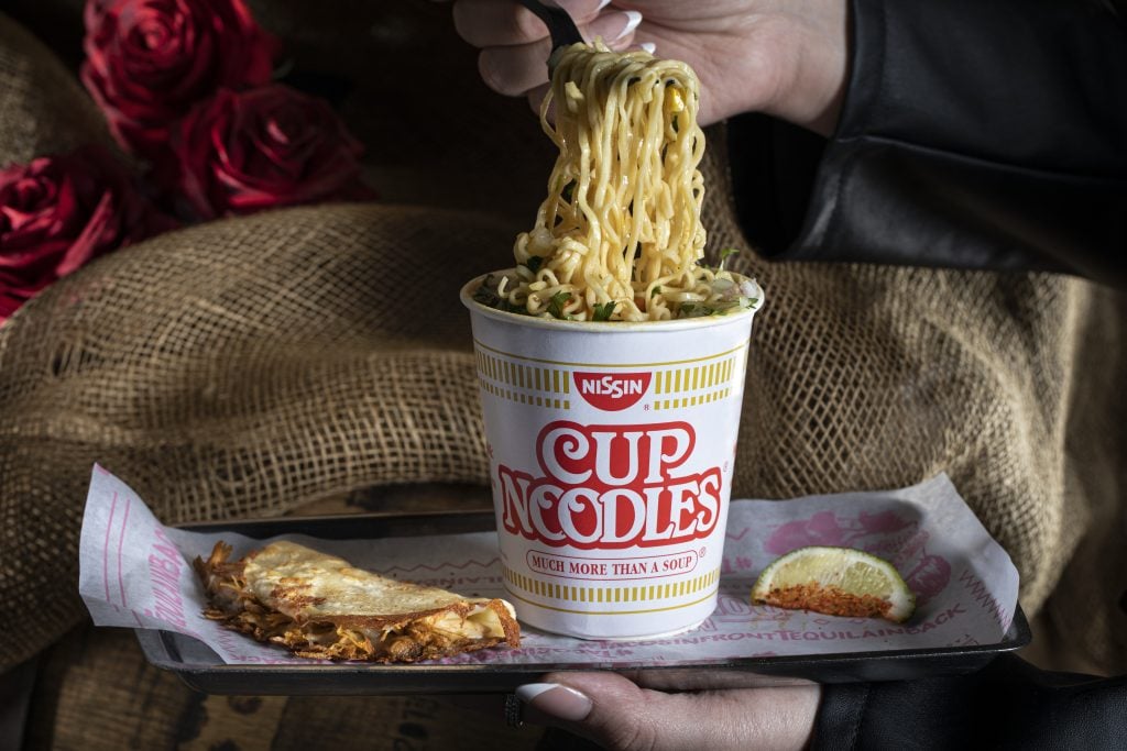 a person holding a cup of noodles