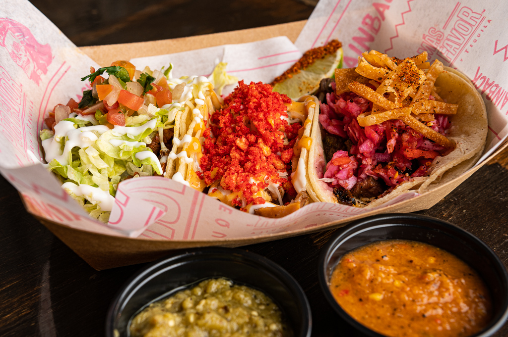 Assorted carnitas tacos in Las Vegas served with salsa and vibrant toppings in a takeout tray