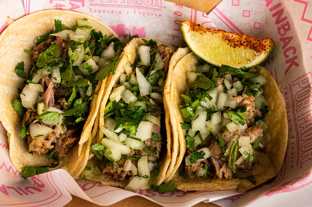 Three citrus grilled chicken tacos topped with fresh onions and cilantro, served with a lime wedge