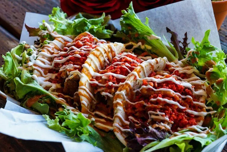 Chicken Tinga Tacos at Mas Por Favor in Las Vegas topped with crema and hot sauce, served with fresh greens.