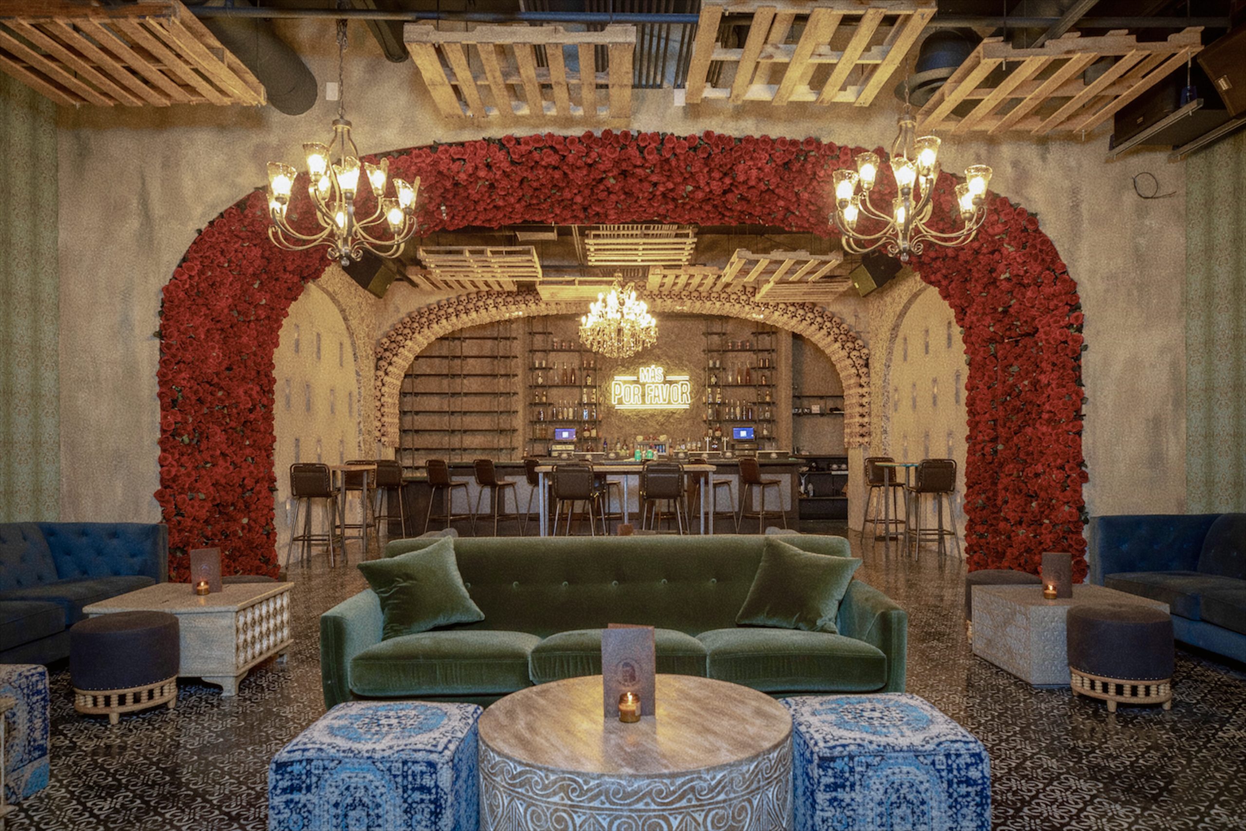 Elegant interior of Mas Por Favor restaurant in Las Vegas, featuring plush seating, floral archways, chandeliers, and a stylish bar in the background