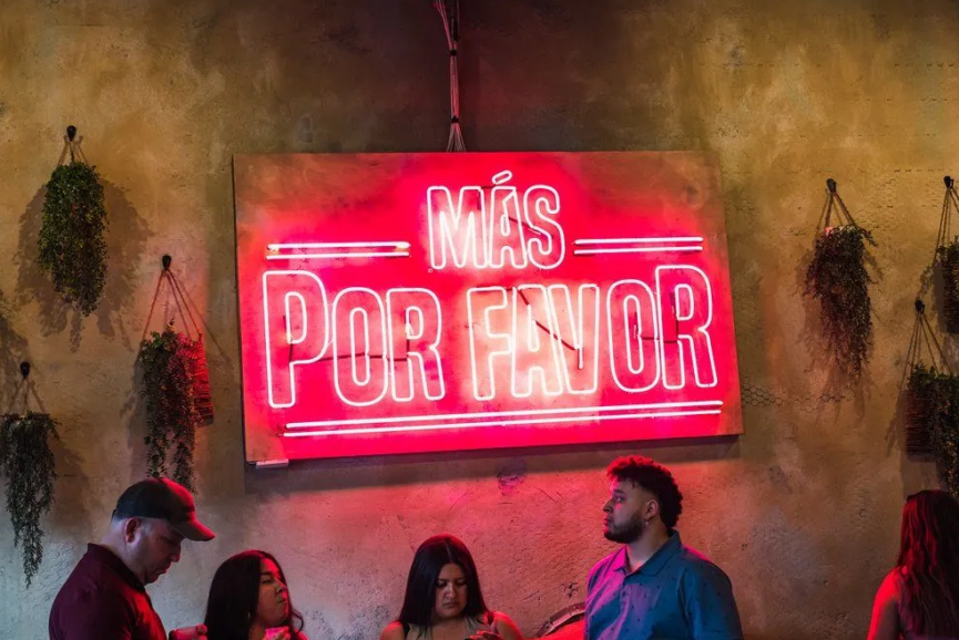 Interior of Más Por Favor in Las Vegas featuring a glowing neon sign and vibrant atmosphere where guests enjoy the best Mexican loaded fries in Las Vegas.