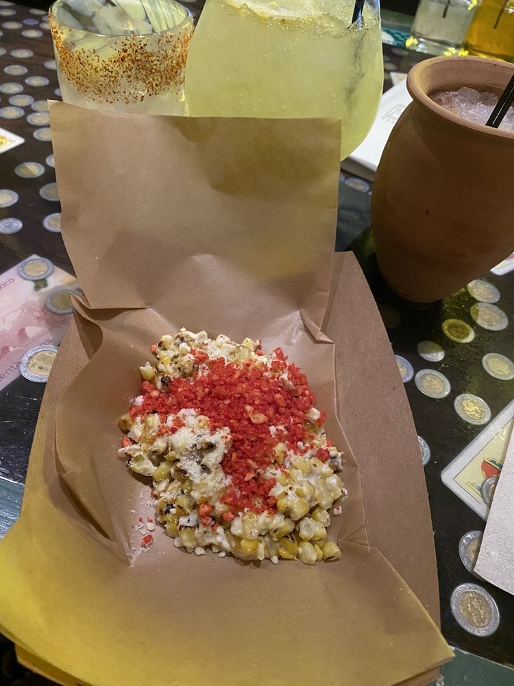 Street-style elotes served at Mas Por Favor in Las Vegas topped with Flaming Hot Cheetos dusting, perfect for anyone searching for authentic Mexican corn nearby